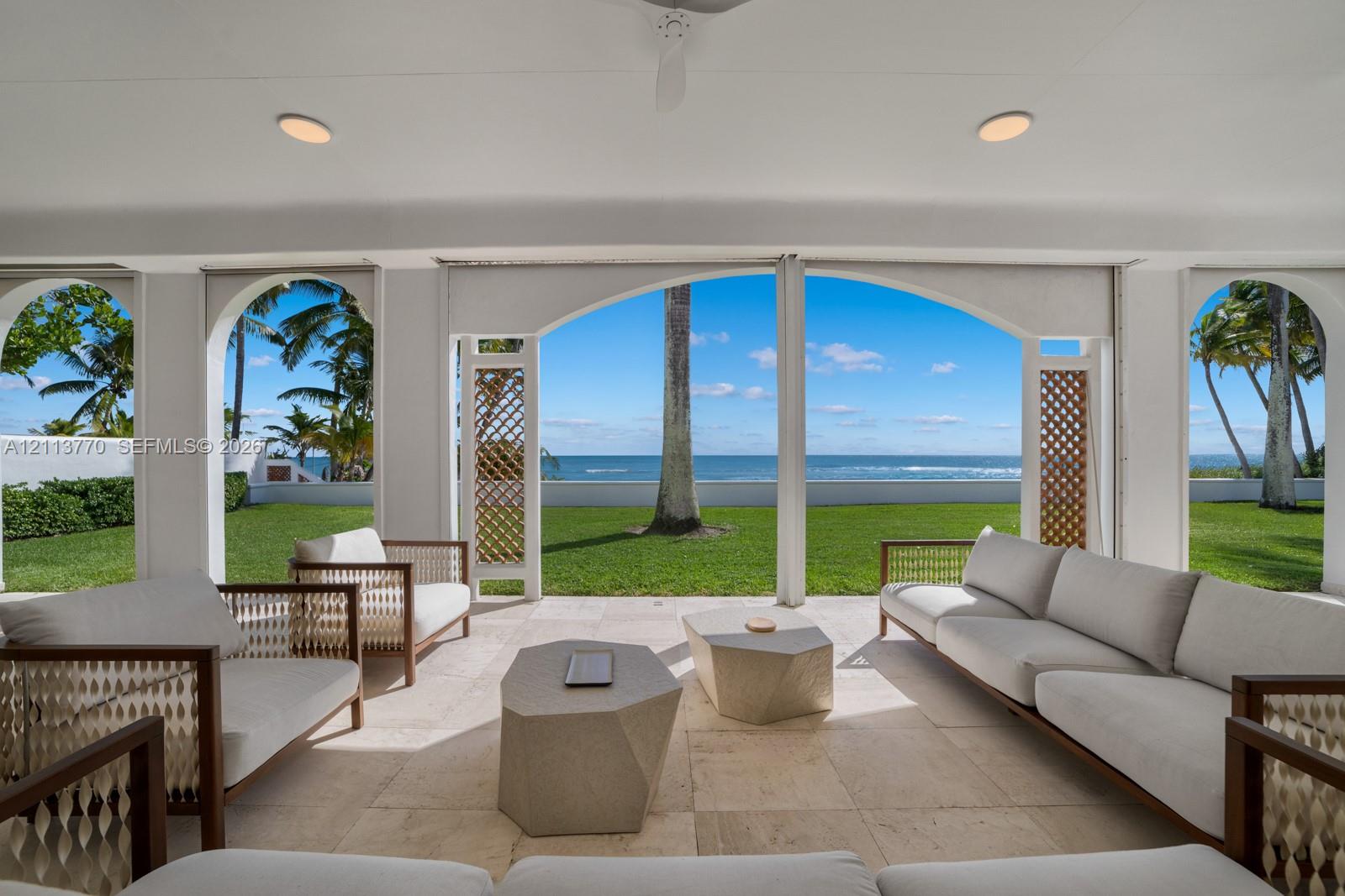 Covered loggia featuring stone flooring, arched openings, recessed lighting, and decorative latticework