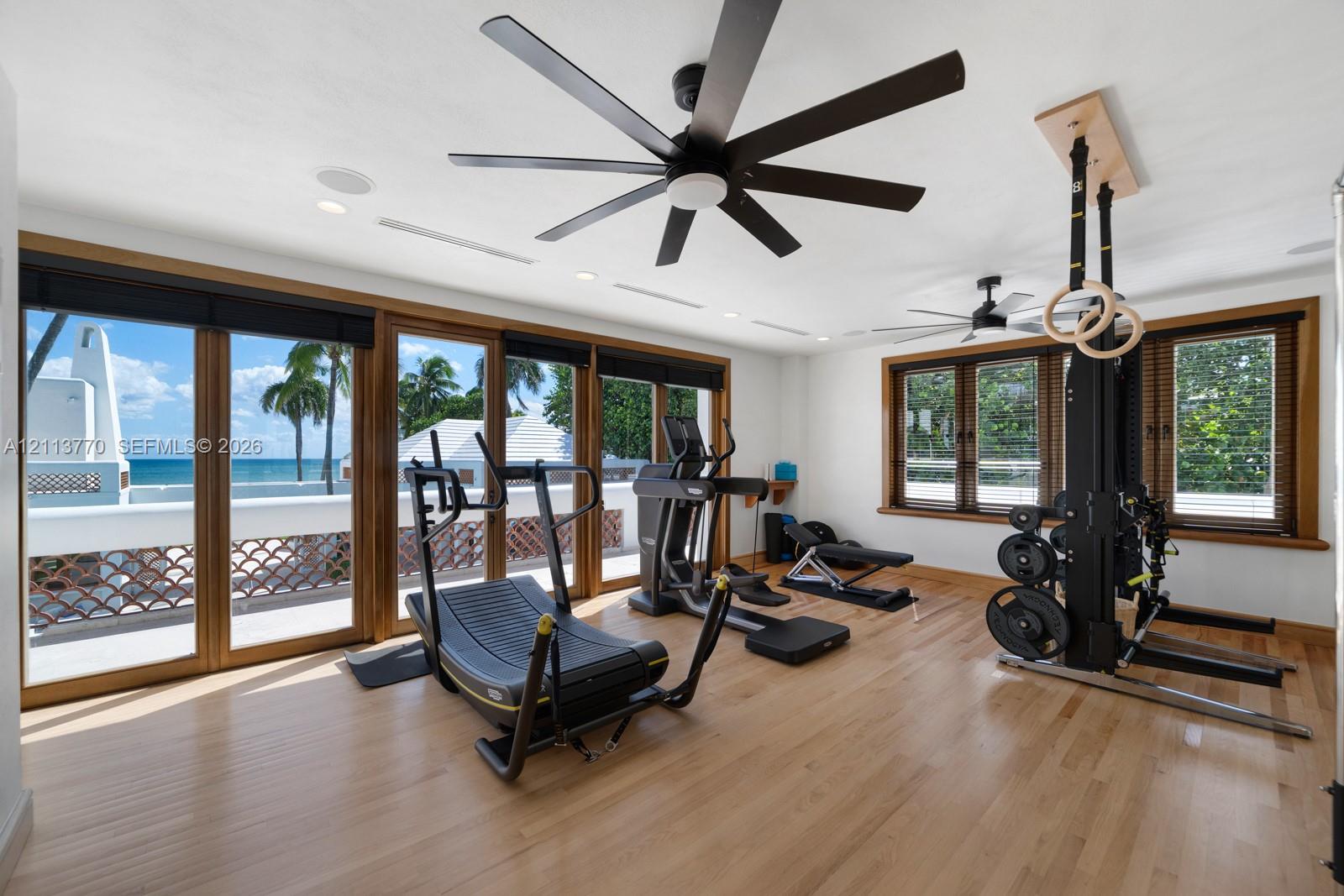 Wood-finish flooring, floor-to-ceiling glass panel doors, recessed ceiling lighting, multi-blade ceiling fans, and natural wood window casing