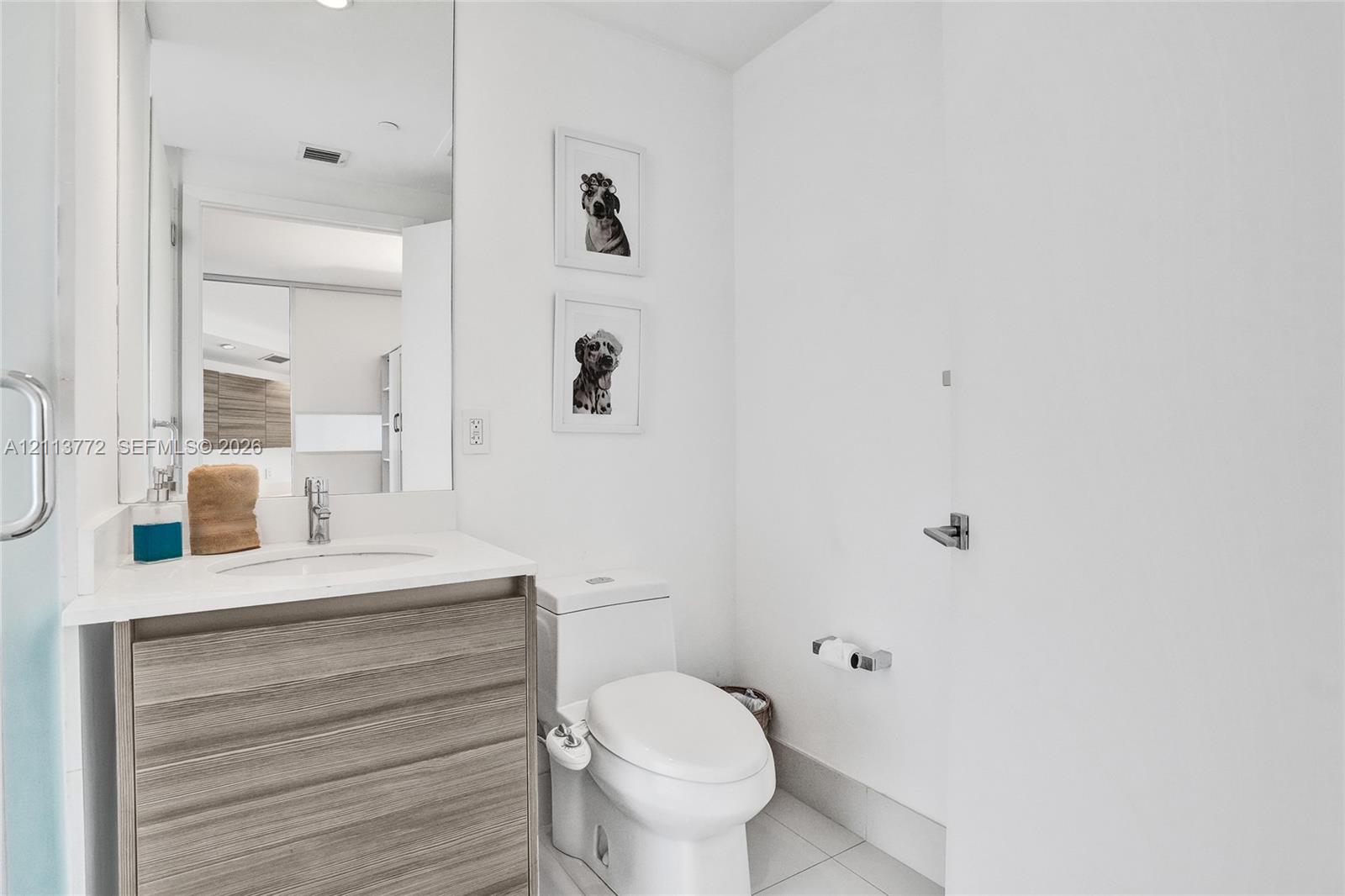 Bathroom featuring a floating wood-finish vanity, integrated white countertop with a recessed basin, chrome single-lever faucet, and large-format wall mirror