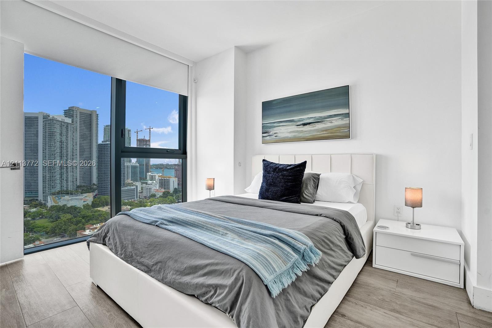 Floor-to-ceiling windows, wood-finish flooring, and high-rise cityscape scenery