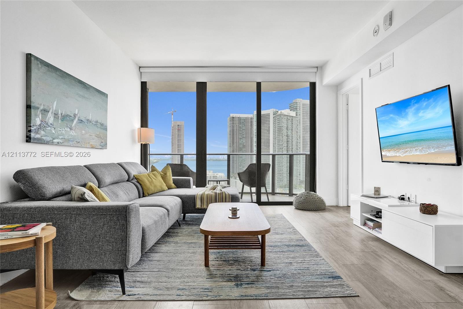 Living area featuring wood-finish flooring, floor-to-ceiling windows, and a private balcony
