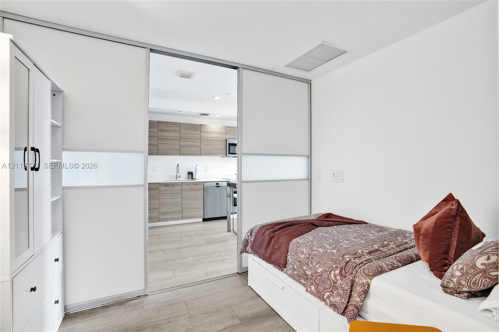 Floor-to-ceiling sliding panels with frosted glass inserts, built-in cabinetry, wood-finish flooring, and recessed ceiling lighting