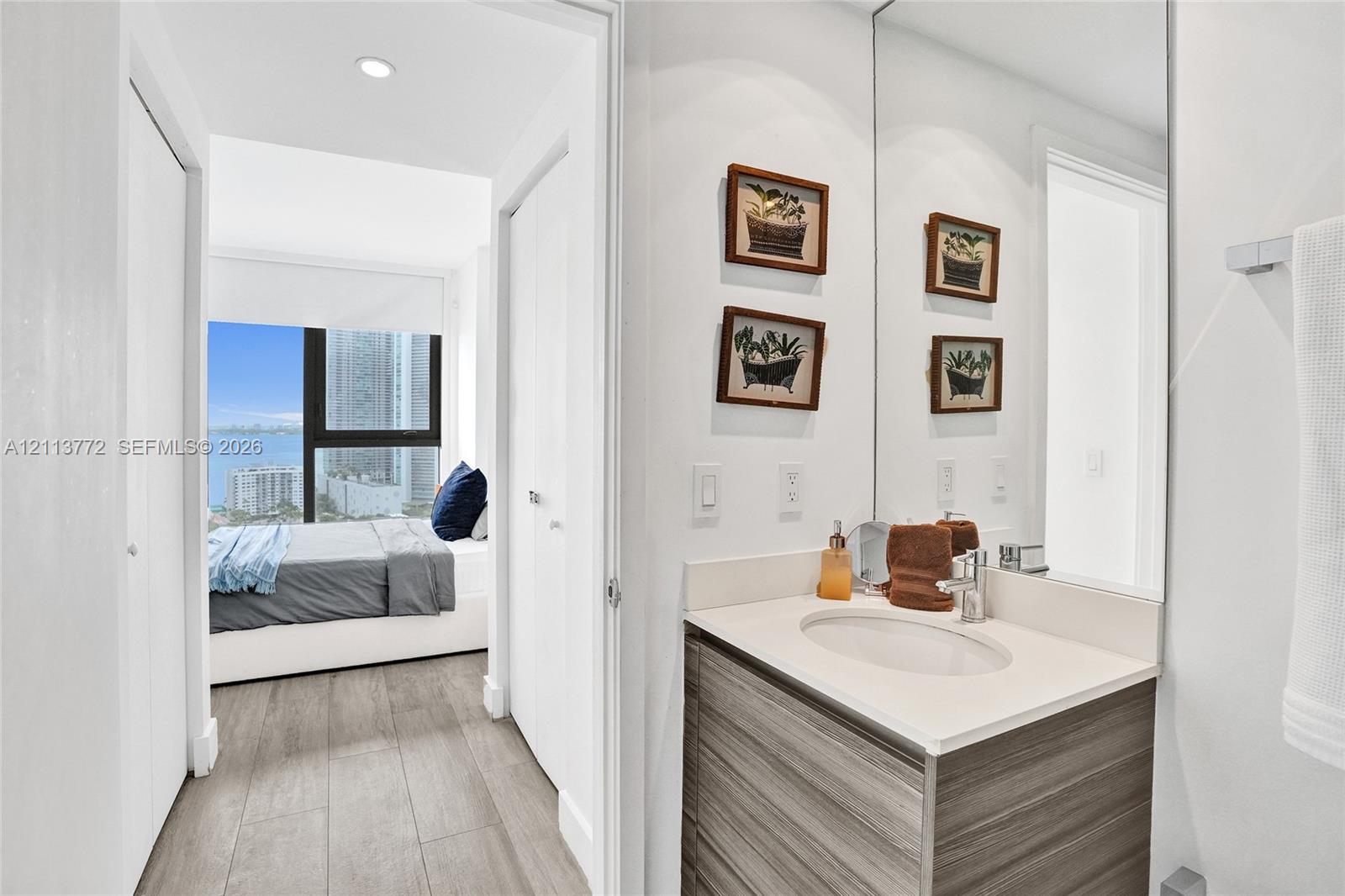 Bathroom featuring a vanity with wood-finish cabinetry, integrated countertop, oval undermount sink, and full-height wall mirror