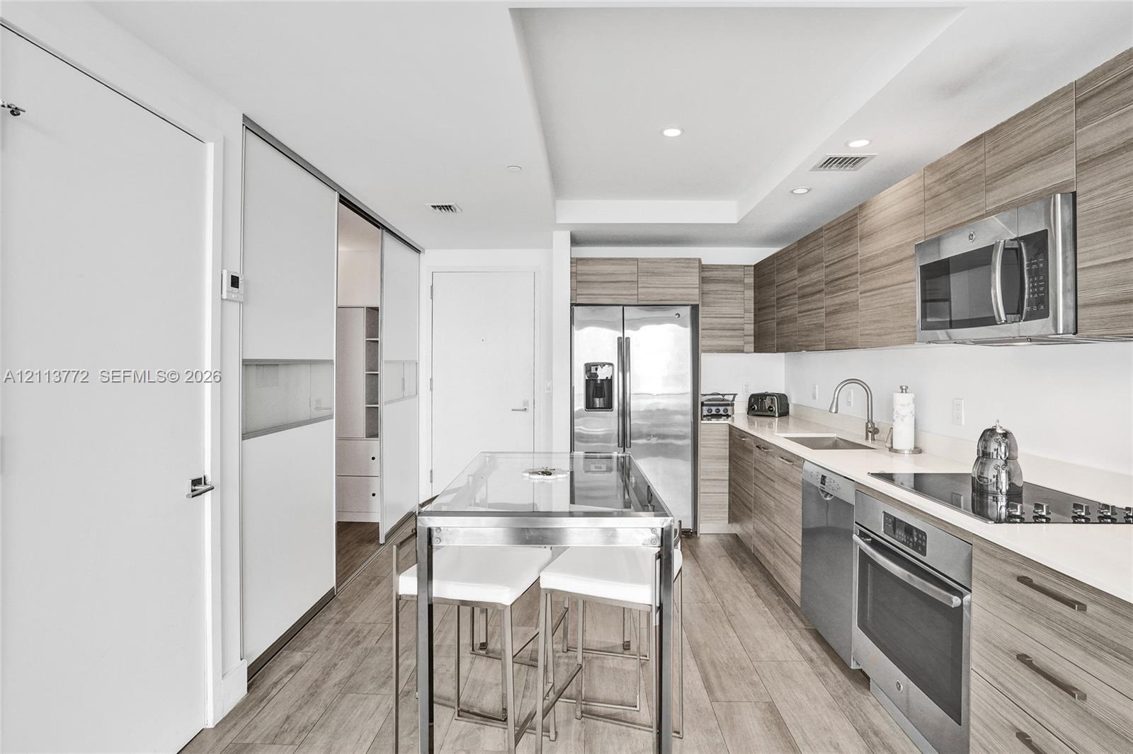 Kitchen featuring horizontal wood-grain cabinetry, stainless steel appliances, solid surface countertops, and wood-finish flooring