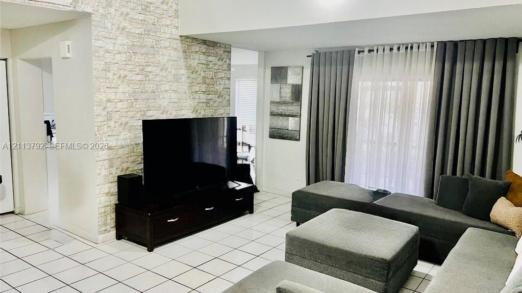 Floor-to-ceiling ston/Users/vishpersaud/Pictures/back yard 3.webpe-veneer accent wall, ceramic tile flooring, and large window treatment