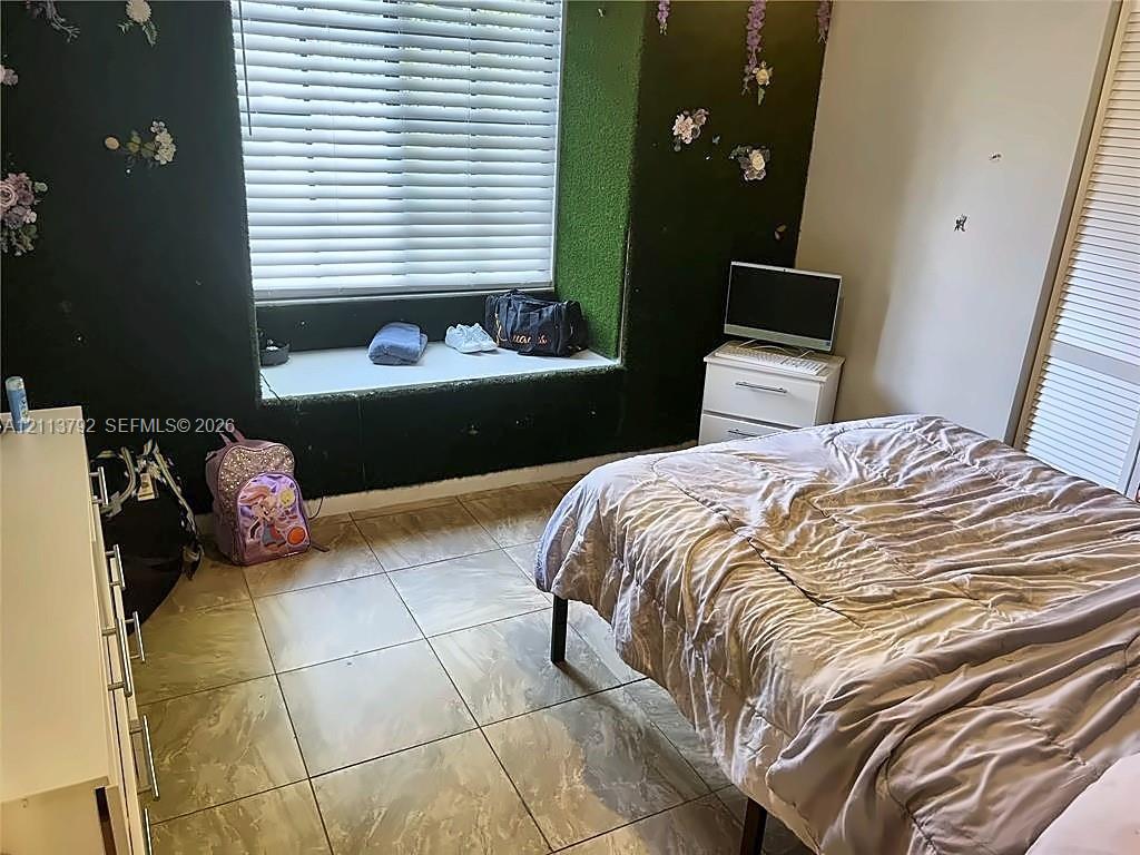 Large-format tile flooring, recessed window seat, and built-in closet with louvred doors