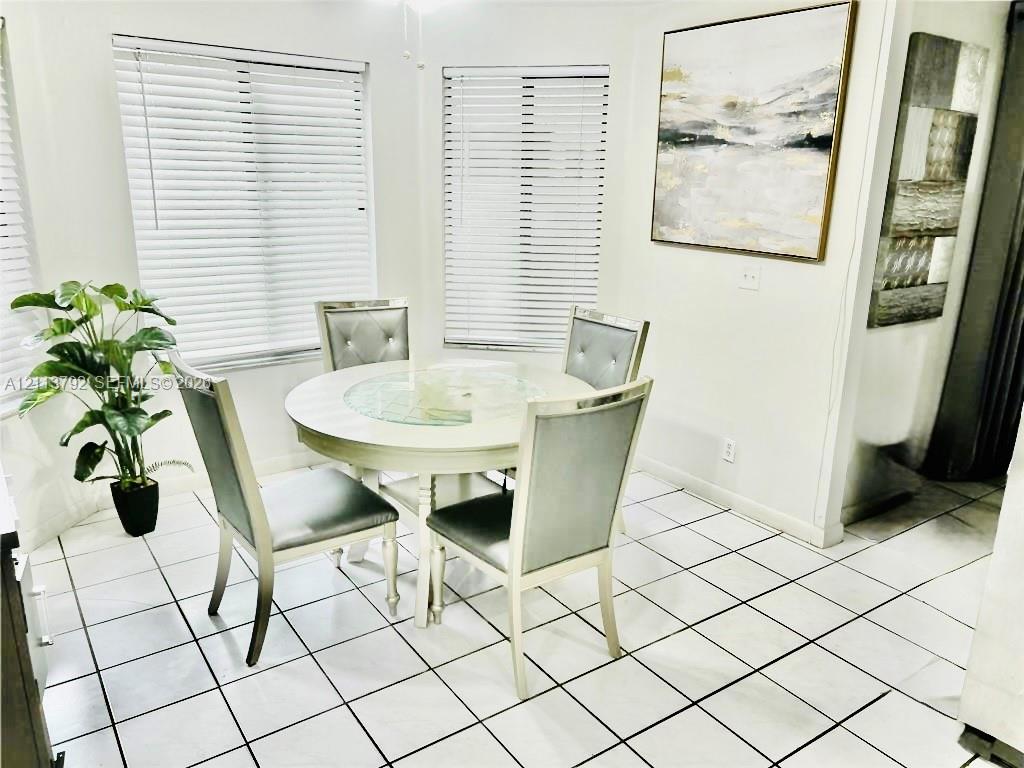 Bright dining area featuring ceramic tile flooring, neutral walls, and multiple windows with installed horizontal blinds