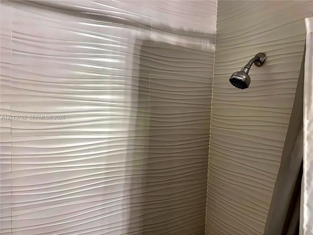 Textured wall tiles featuring a horizontal wave pattern and a wall-mounted shower head with a metallic finish