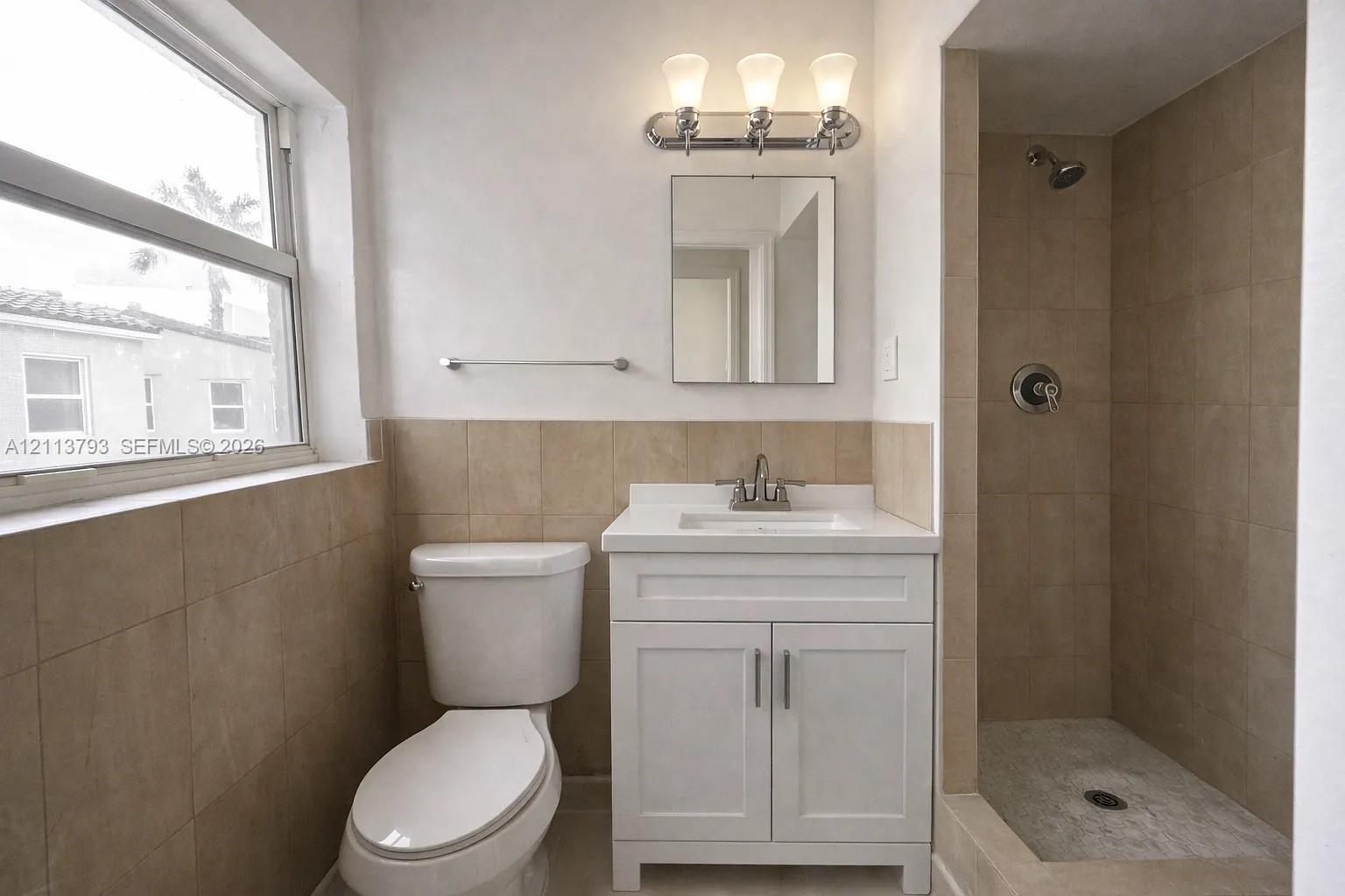 Bathroom featuring a white vanity cabinet, square undermount sink, three-light polished chrome fixture, and walk-in tiled shower Bathroom featuring a white vanity cabinet, square undermount sink, three-light polished chrome fixture, and walk-in tiled shower
