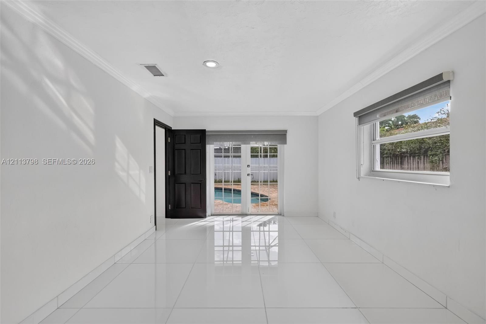 Interior room featuring large-format tile flooring, recessed lighting, crown molding, and double glass-paneled exterior doors with roller shades