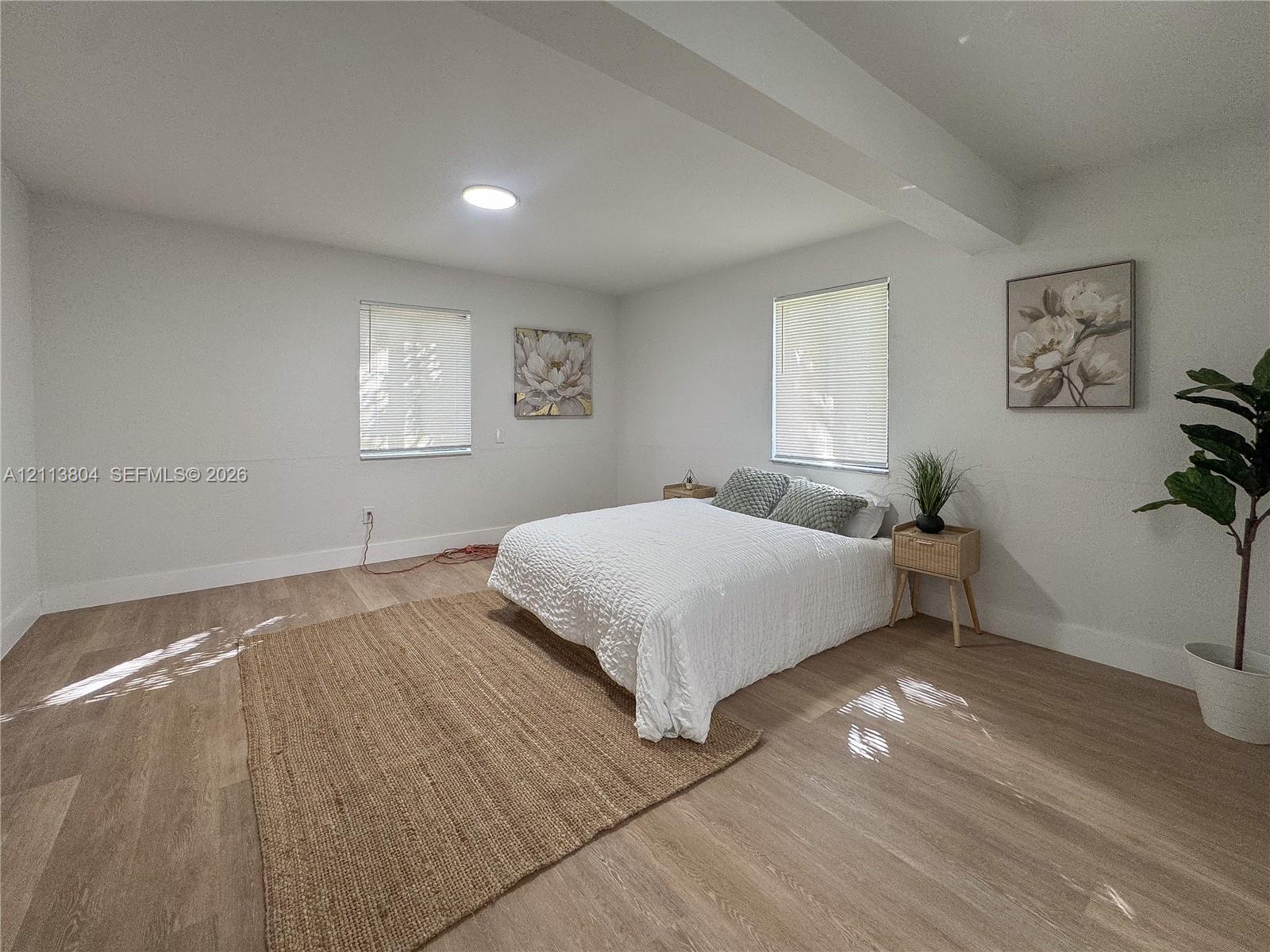 Spacious interior featuring wood-finish flooring, neutral wall tones, two windows with horizontal blinds, and recessed ceiling lighting
