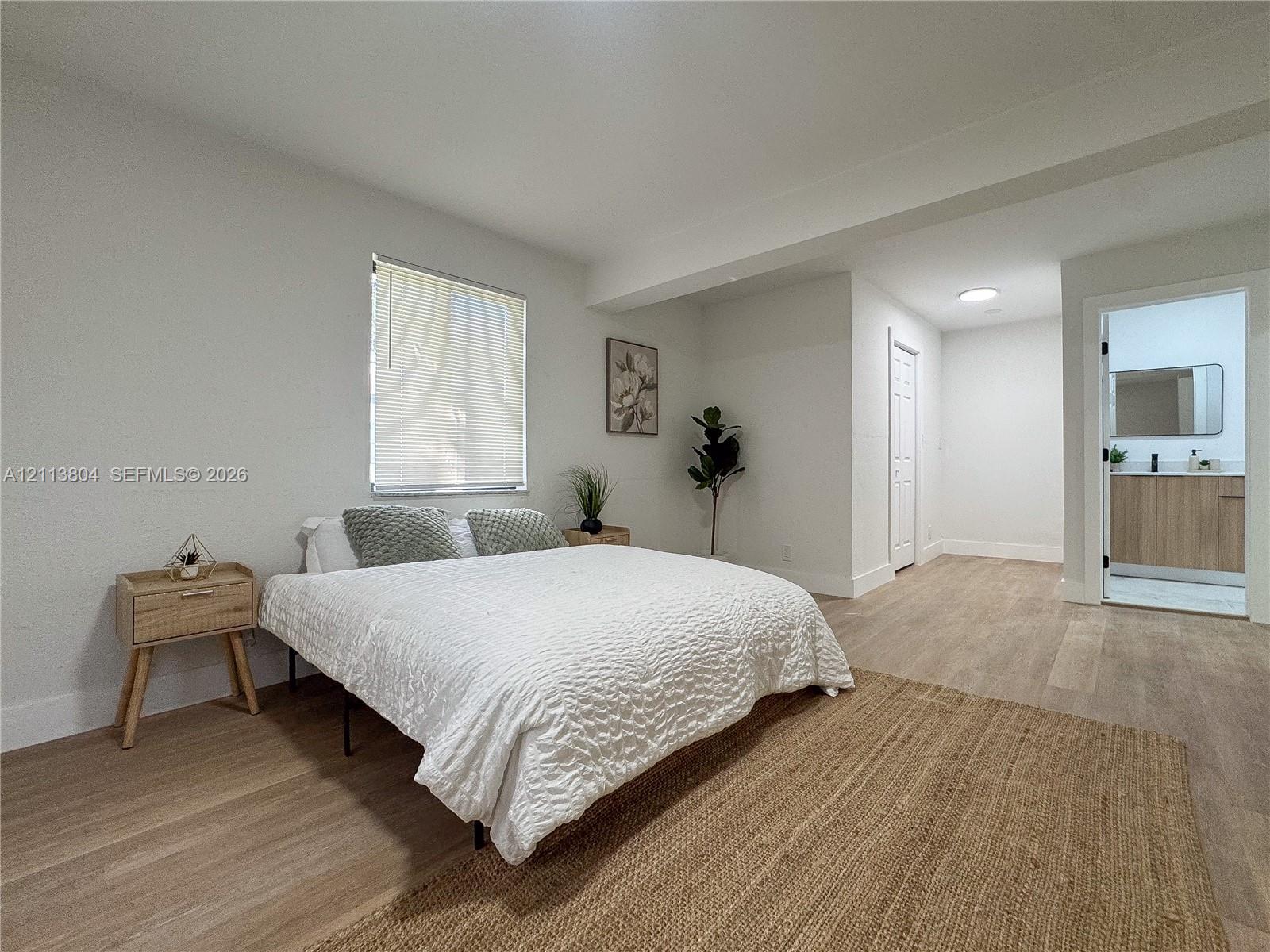 Neutral interior featuring light-tone wood-finish flooring, recessed lighting, and a window with integrated blinds