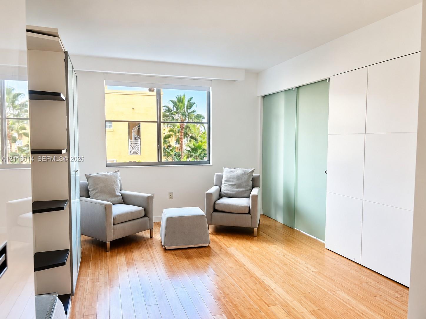 Wood-finish flooring, floor-to-ceiling built-in white cabinetry, and sliding opaque glass-panel doors