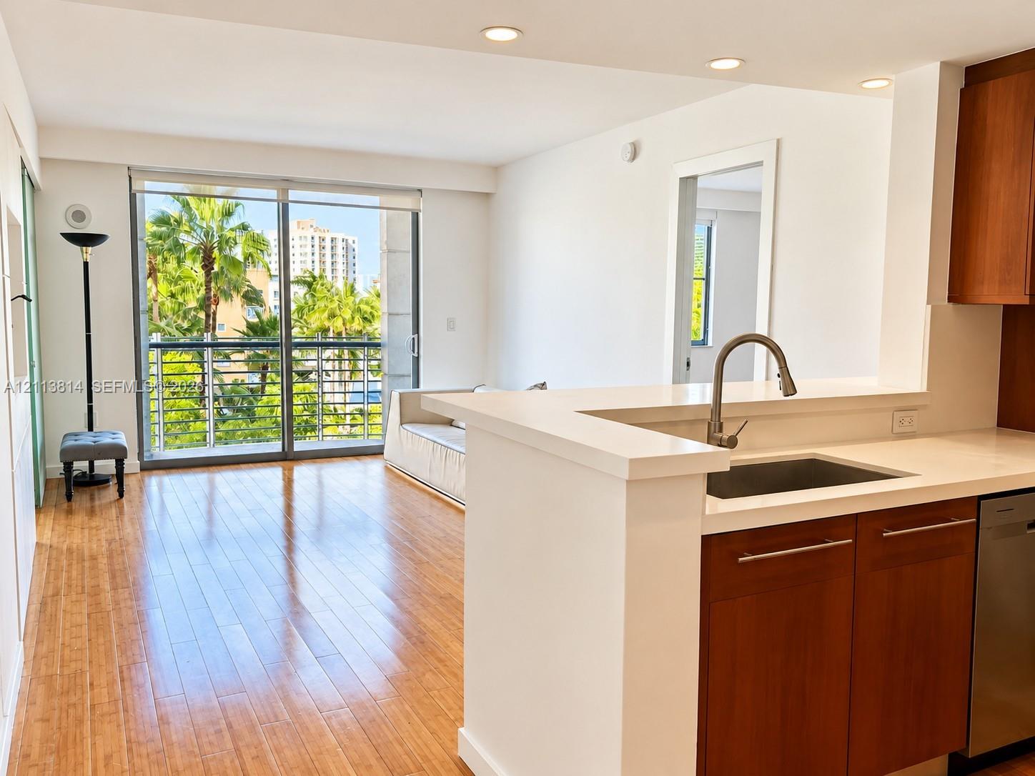 Kitchen featuring a breakfast bar with stone countertops, an undermount sink with a gooseneck faucet, wood-finish cabinetry, recessed lighting, and wood-finish flooring