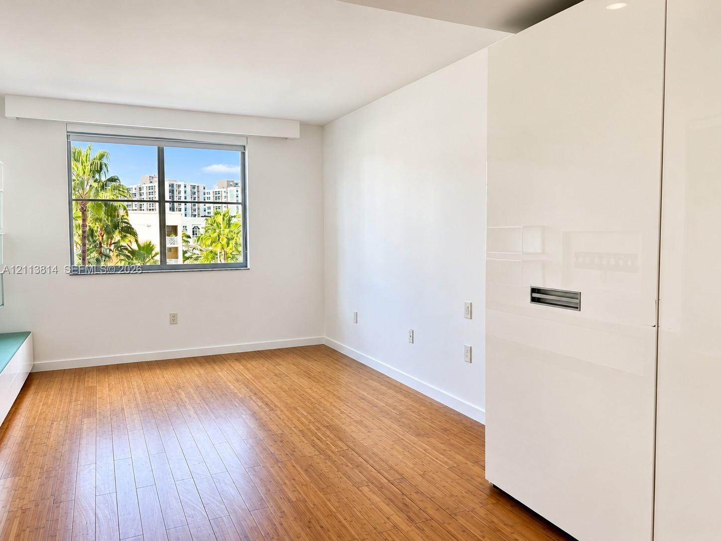 Wood-finish flooring, high-gloss white built-in cabinetry, and large-format windows