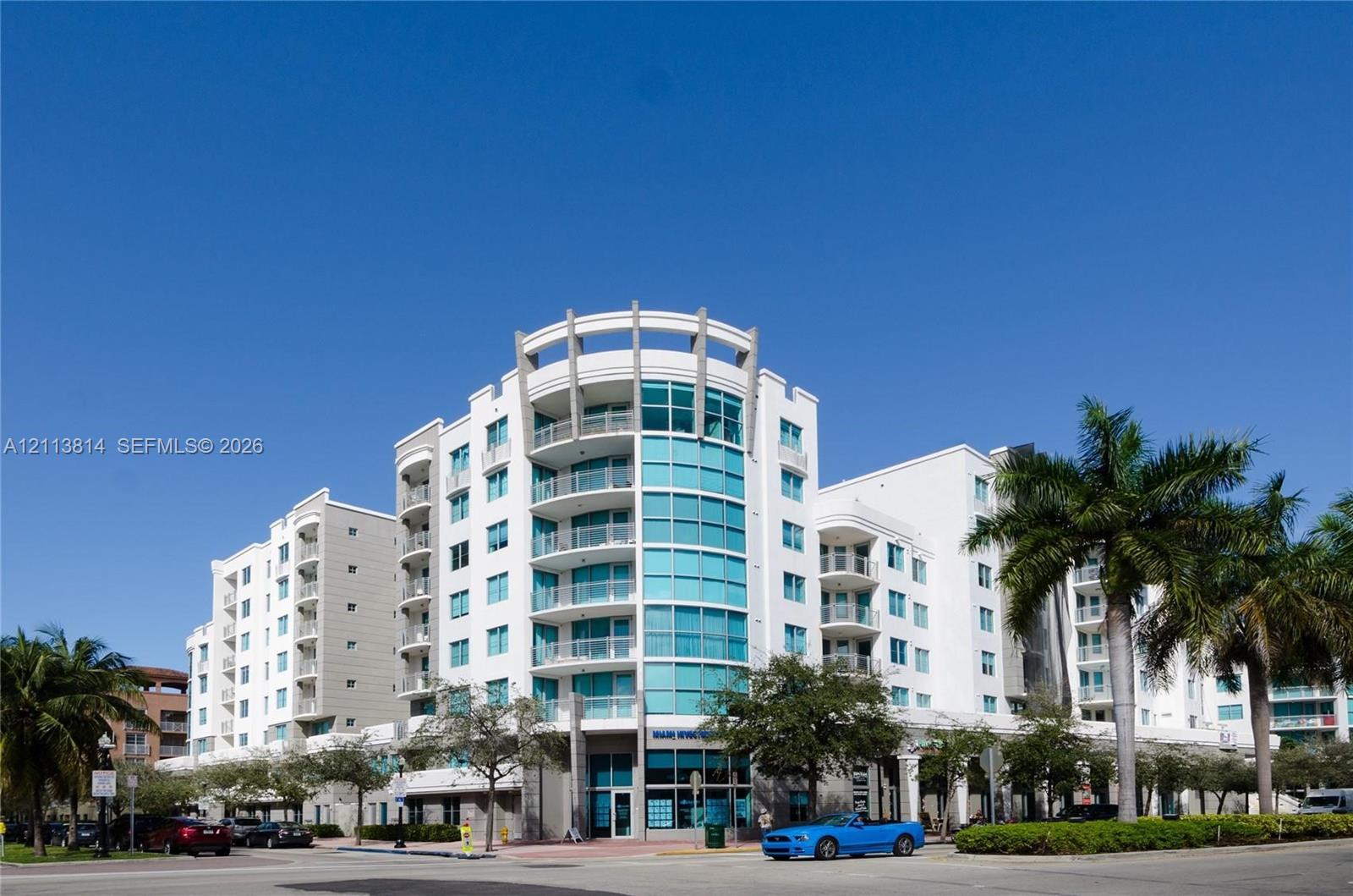 Multi-story building exterior featuring a curved facade, expansive glass windows, and private balconies