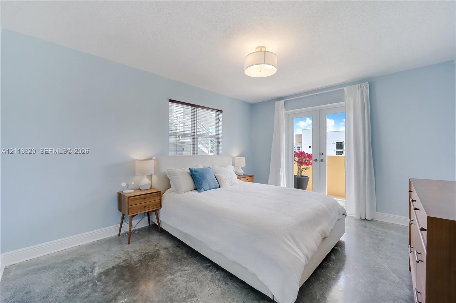 Polished concrete flooring, recessed window, glass-paneled double doors, and a central drum-style ceiling light fixture Polished concrete flooring, recessed window, glass-paneled double doors, and a central drum-style ceiling light fixture