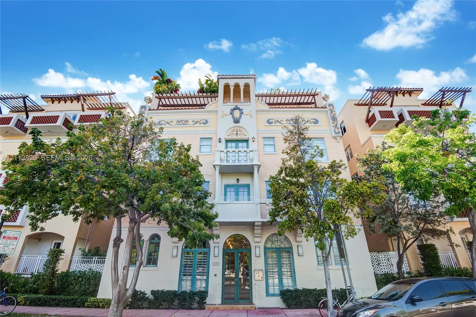 Mediterranean-style exterior featuring decorative molding, a prominent center balcony, rooftop pergola structures, and arched entryway Mediterranean-style exterior featuring decorative molding, a prominent center balcony, rooftop pergola structures, and arched entryway