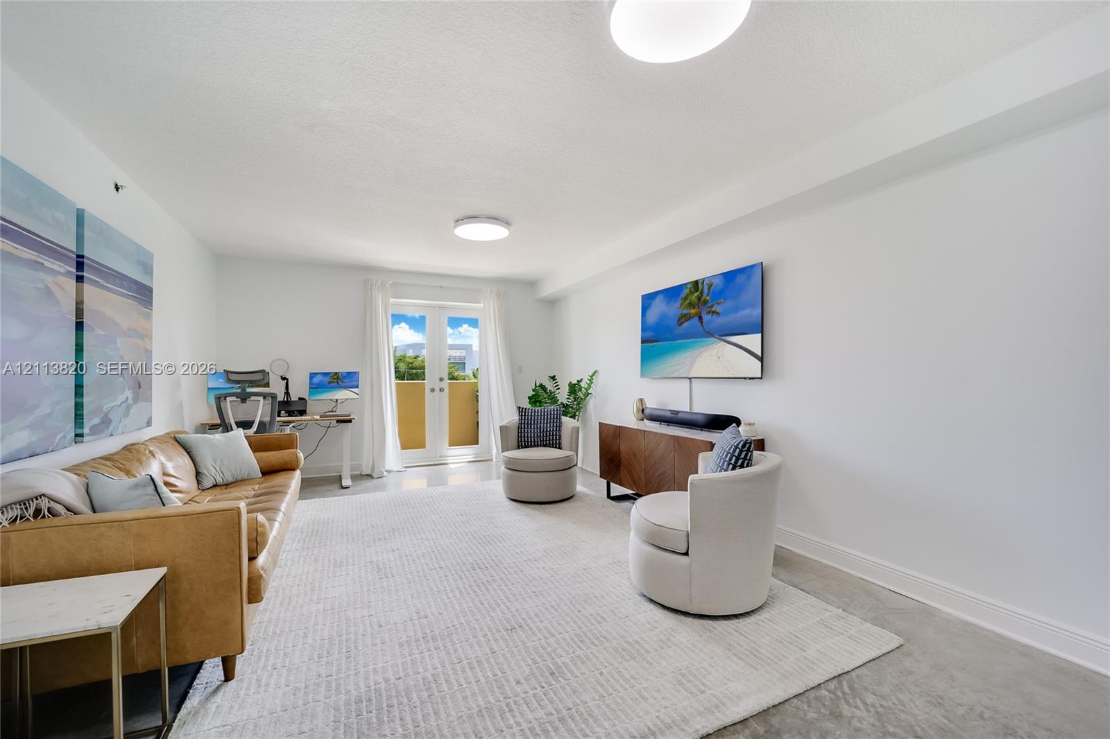 Neutral-toned interior space featuring polished concrete flooring, white walls, and French doors providing access to an exterior balcony Neutral-toned interior space featuring polished concrete flooring, white walls, and French doors providing access to an exterior balcony
