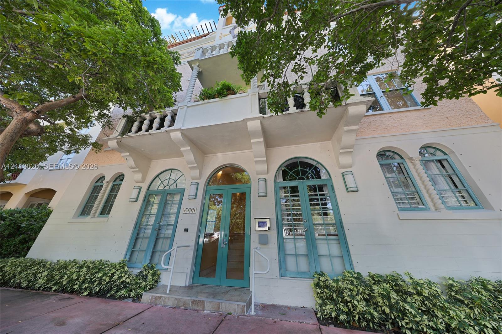 Exterior facade featuring arched windows with spiral column detailing, stone-textured masonry, and a cantilevered balcony with balustrade railings
