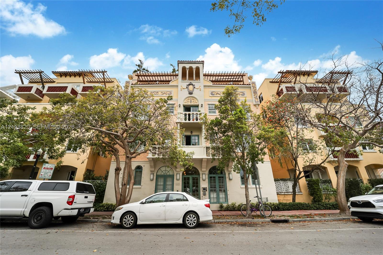 Multi-story exterior featuring a Mediterranean-inspired facade, arched architectural details, integrated balconies with metal railings, and rooftop pergolas