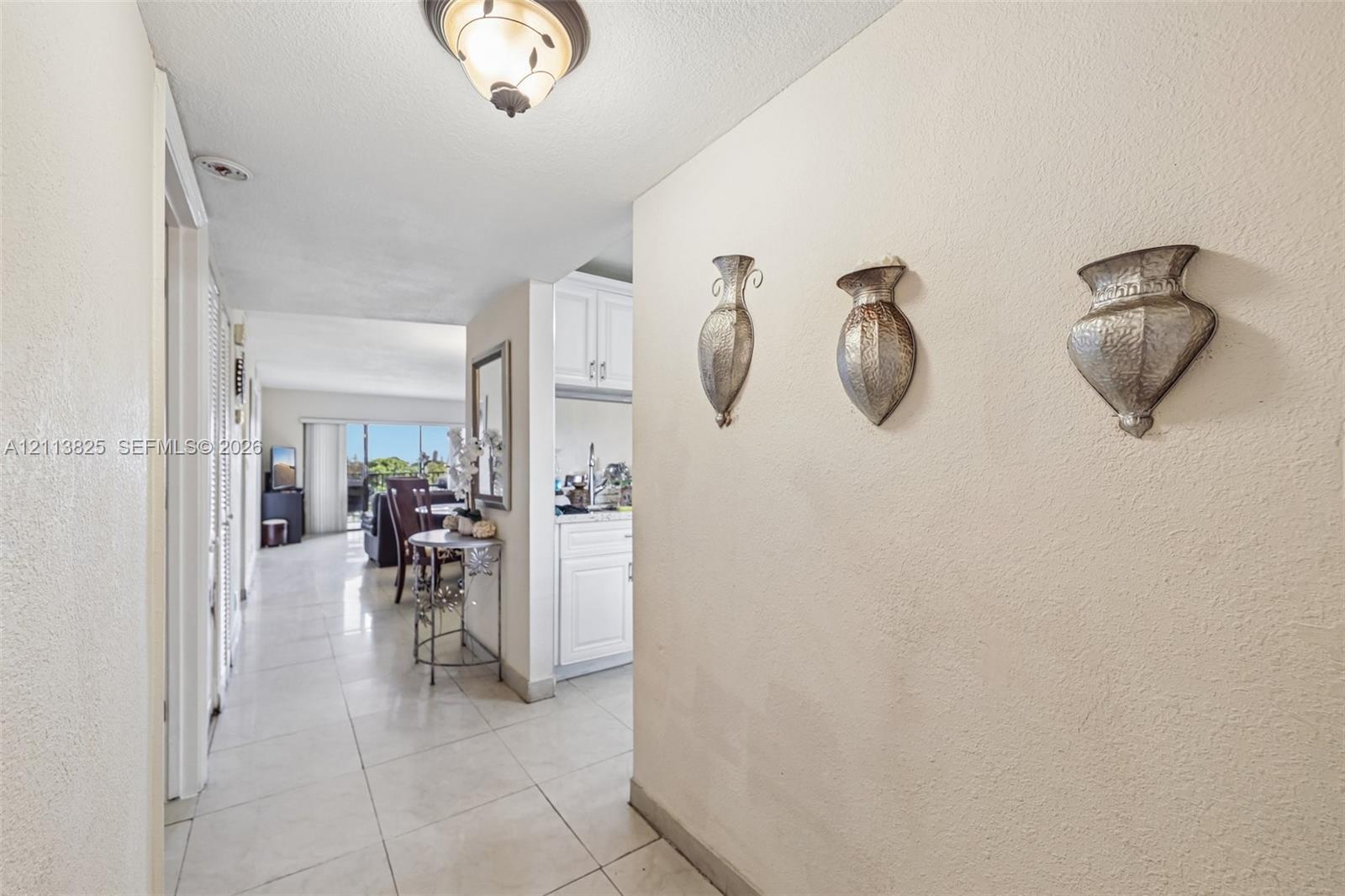 Neutral-toned interior featuring oversized tile flooring, semi-flush mount ceiling lighting, and crisp white cabinetry