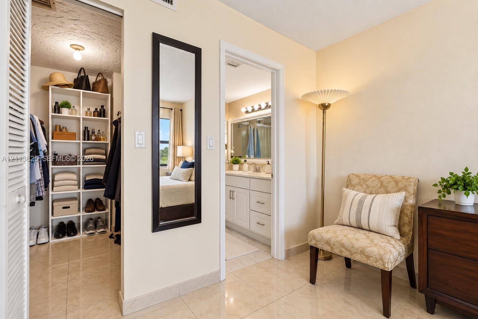 Walk-in closet featuring built-in white shelving, polished tile flooring, and a louvered door