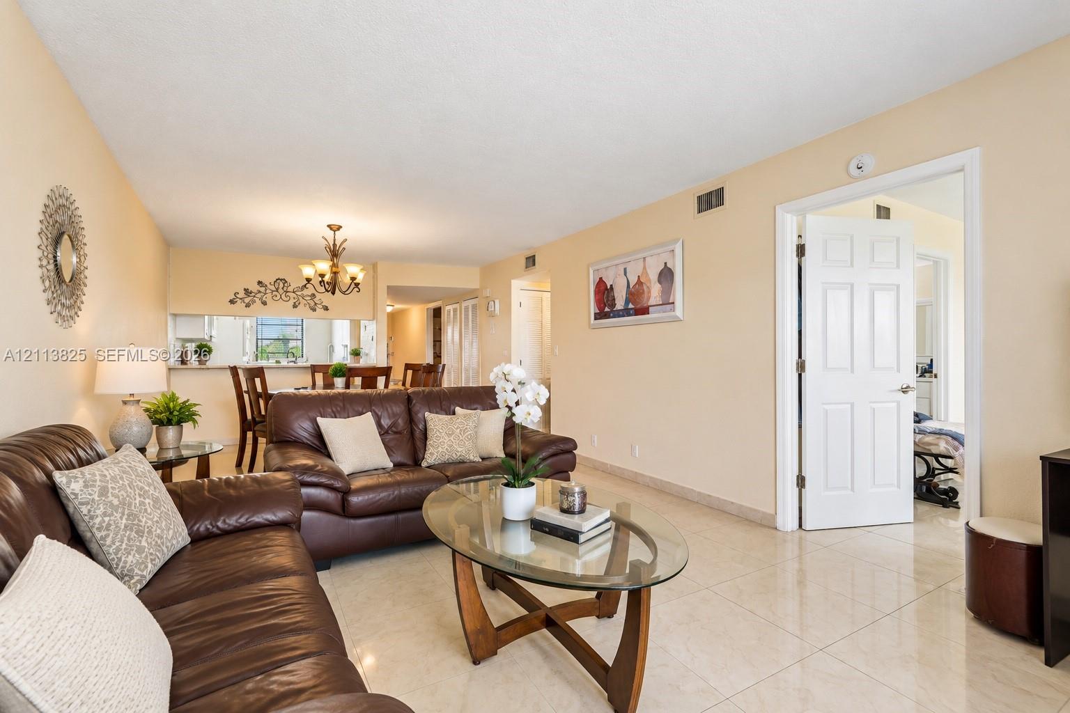 Neutral-toned interior featuring large-format tile flooring, a six-panel interior door, and a multi-arm chandelier
