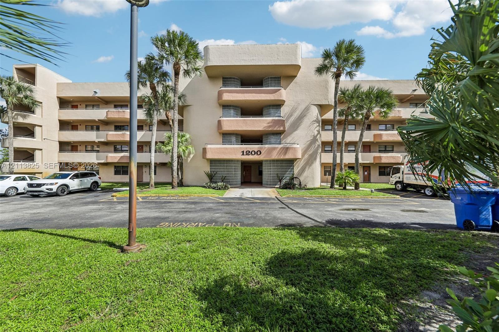 Multi-story exterior featuring a stucco facade, stacked private balconies, glass block accents, and mature palm trees Multi-story exterior featuring a stucco facade, stacked private balconies, glass block accents, and mature palm trees