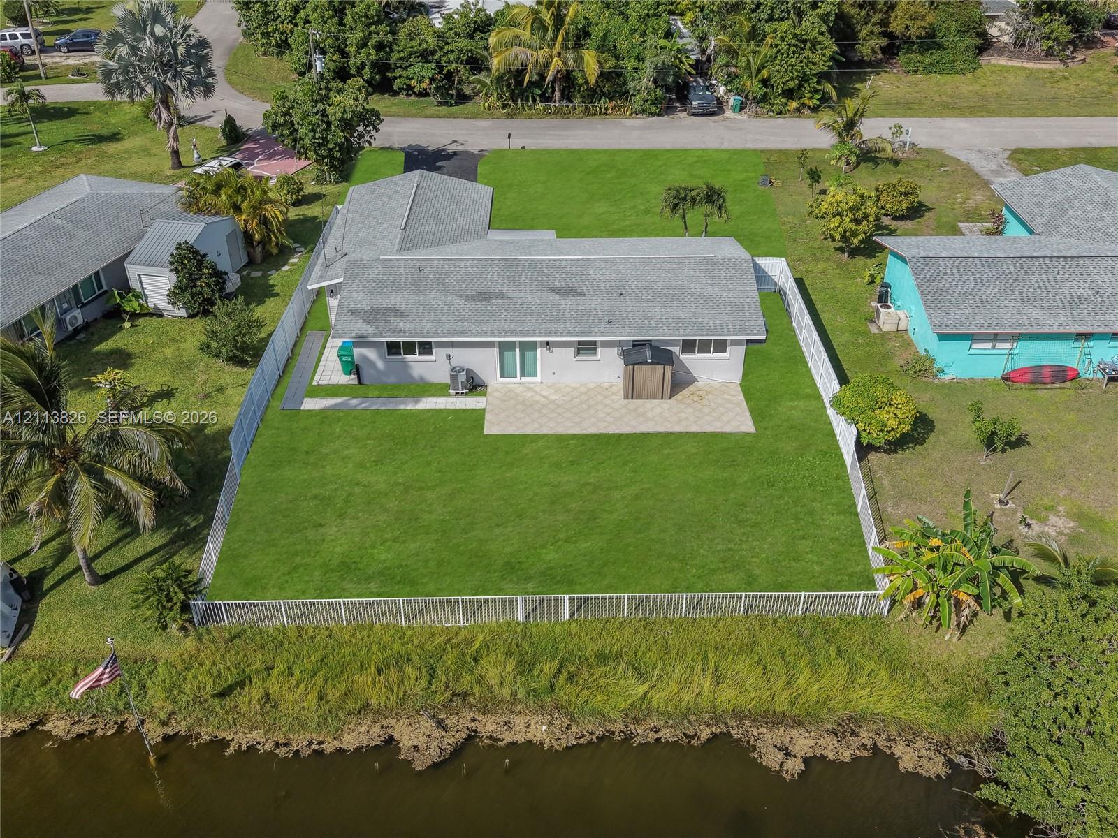 Waterfront property featuring a fenced backyard, paved patio, and grass lawn Waterfront property featuring a fenced backyard, paved patio, and grass lawn