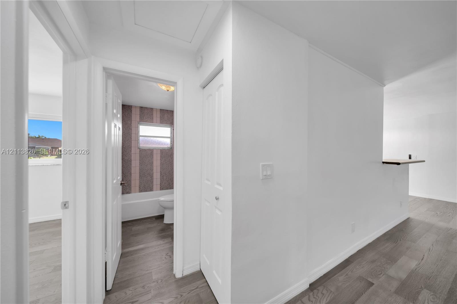 Interior space featuring wood-finish flooring, white paneled doors, and a built-in wall shelf