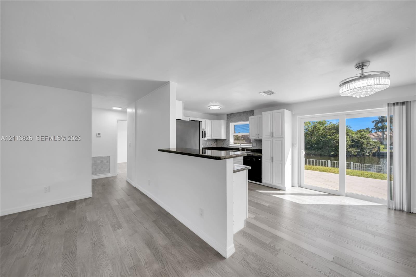Kitchen featuring white cabinetry, stone-finish countertops, stainless steel appliances, wood-finish flooring, and sliding glass doors to the exterior