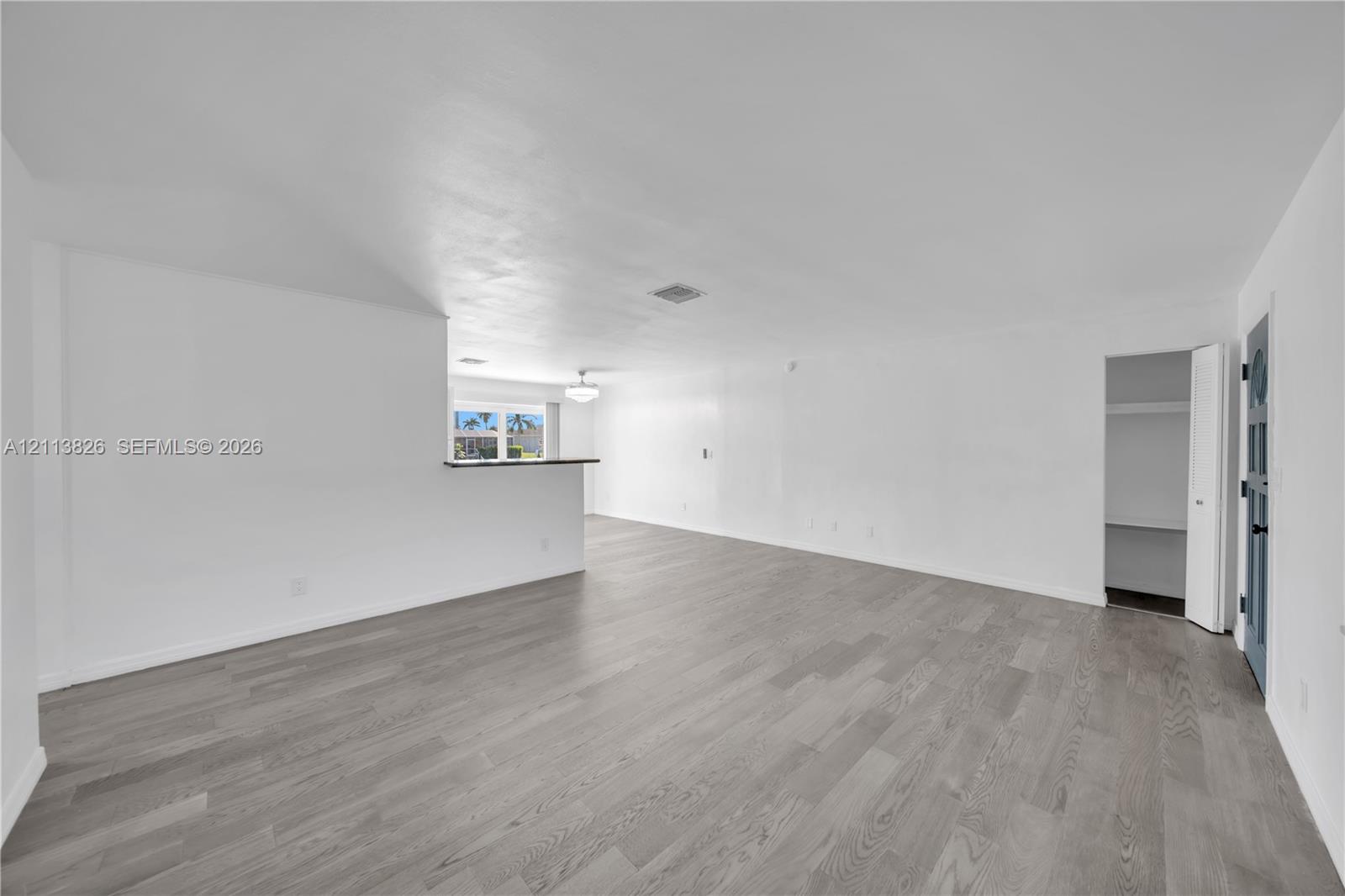 Open-concept living space featuring wood-finish flooring, a built-in partition wall, and a multi-panel door with glass inserts