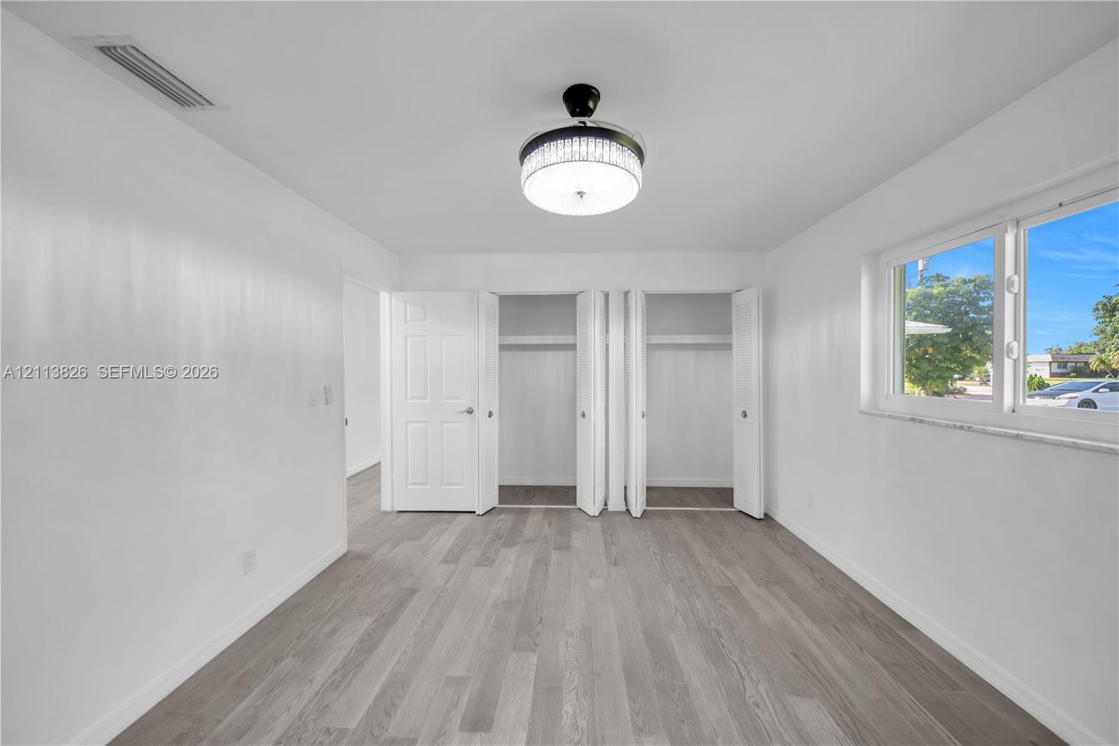 Room featuring wood-finish flooring, dual bi-fold closets, and a central drum-style ceiling fixture