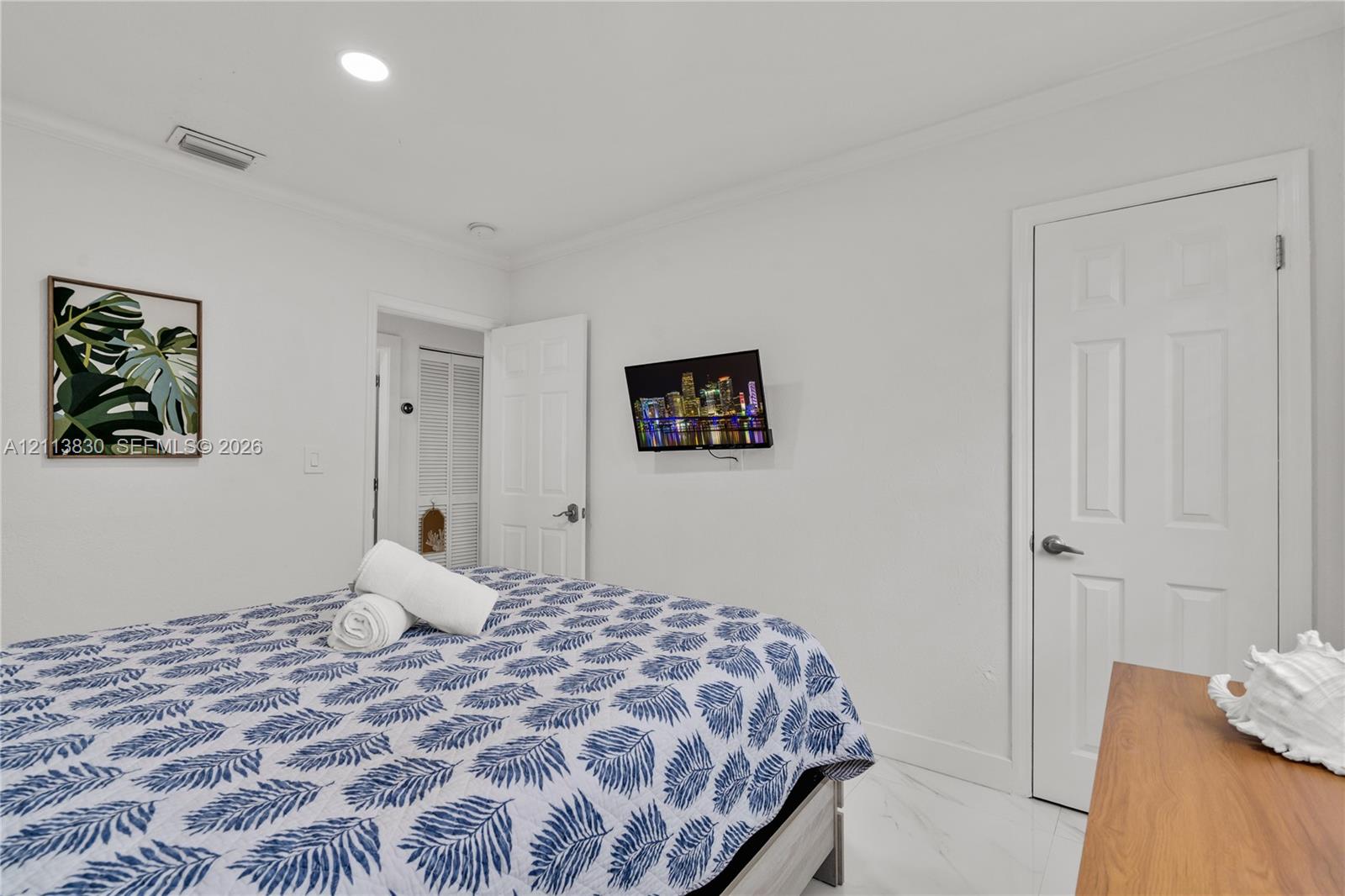 Neutral-toned interior featuring recessed lighting, smooth-finish ceilings with crown molding, six-panel interior doors, and polished stone-finish tile flooring