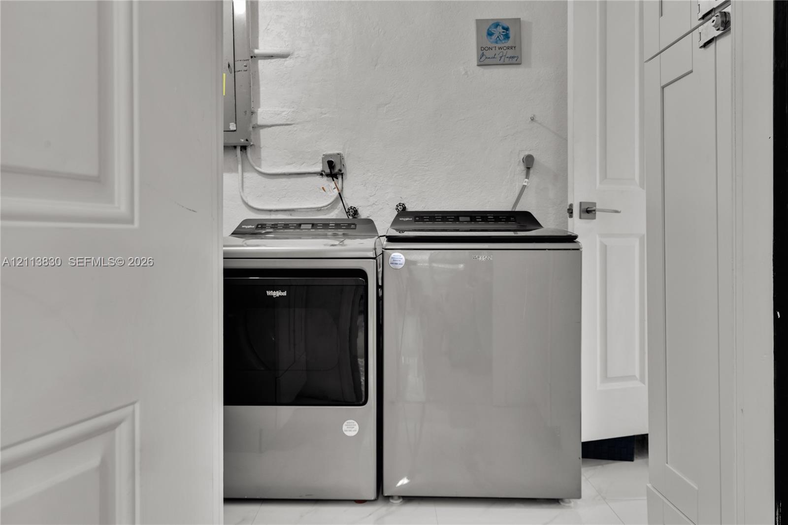 Dedicated utility area featuring panel-style interior doors, light-toned tile flooring, and built-in cabinetry