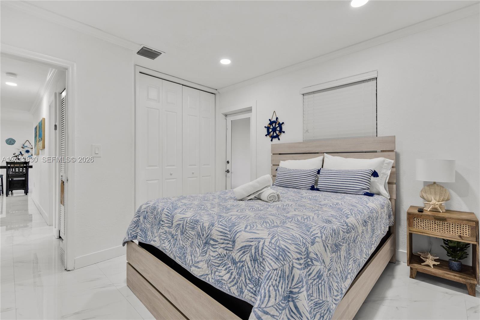 Neutral-toned interior featuring gloss-finish tile flooring, recessed ceiling lighting, and built-in closet storage with double-panel doors