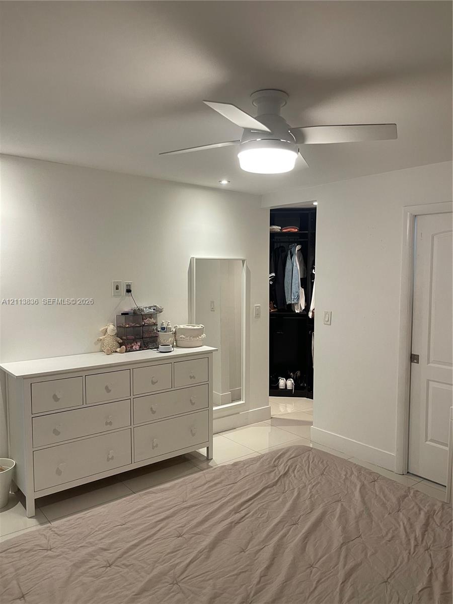 Flush-mount ceiling fan with integrated lighting, polished tile flooring, recessed ceiling light, and built-in closet cabinetry