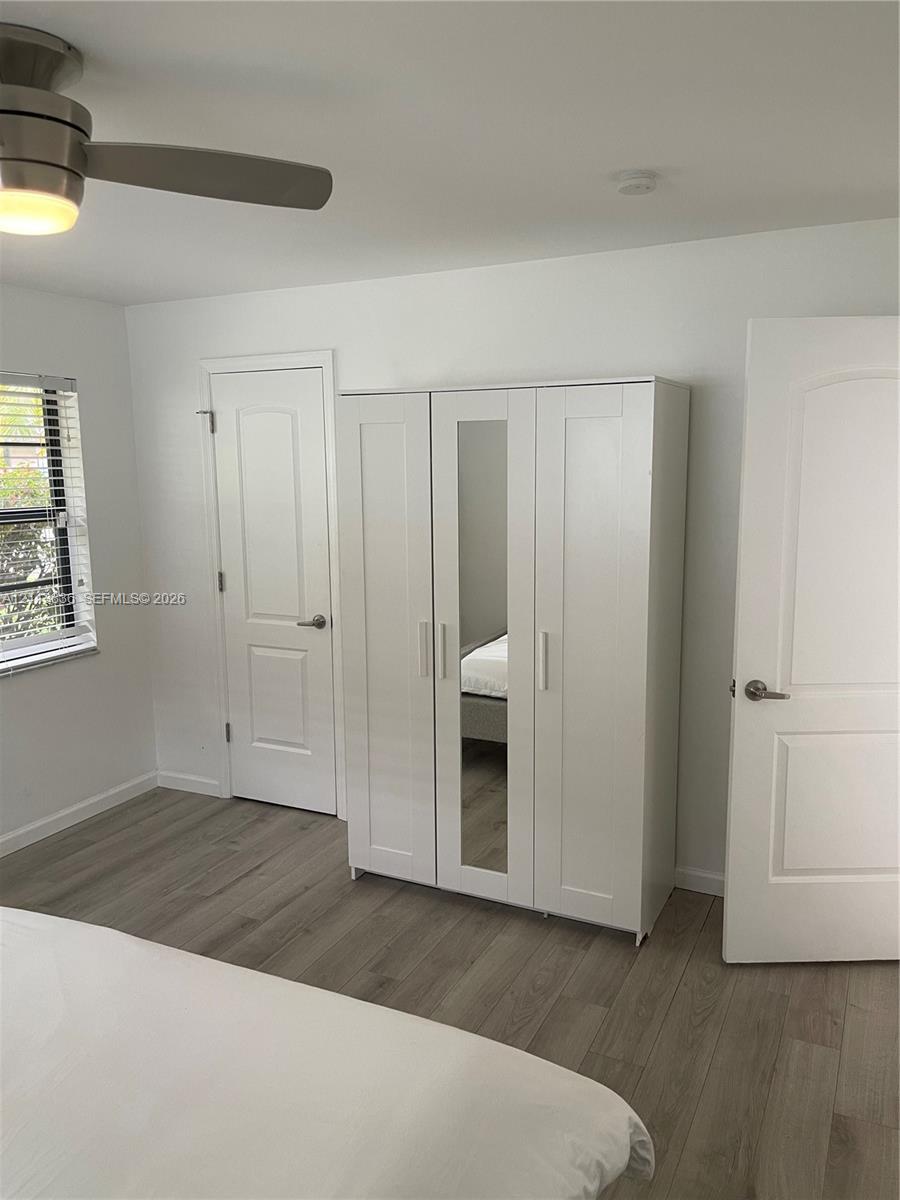 Neutral-toned wood-finish flooring, brushed nickel ceiling fan with integrated lighting, and two-panel interior doors with lever-style hardware