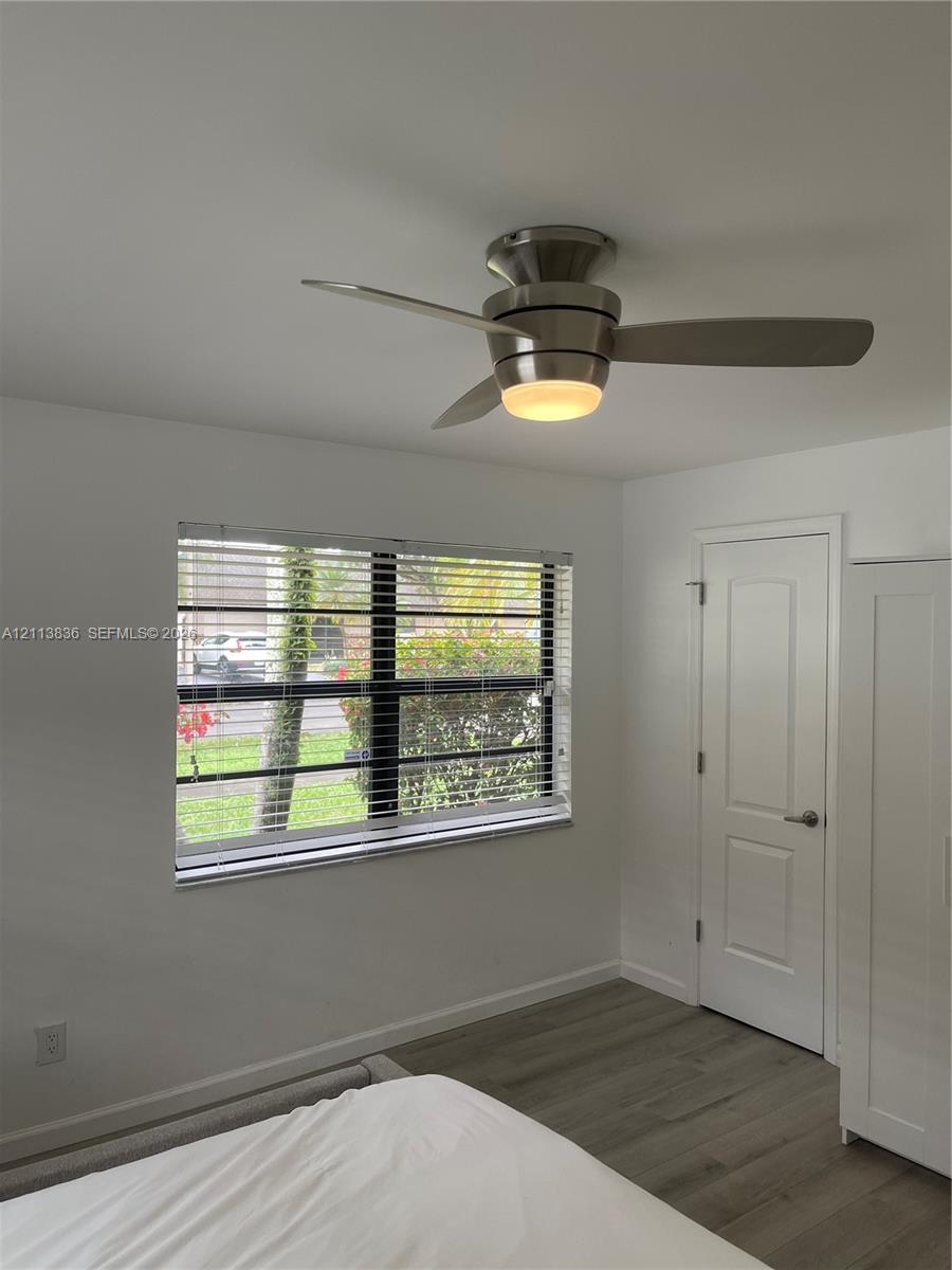 Flush-mount brushed nickel ceiling fan with integrated lighting, wood-finish flooring, and single-hung window with horizontal blinds