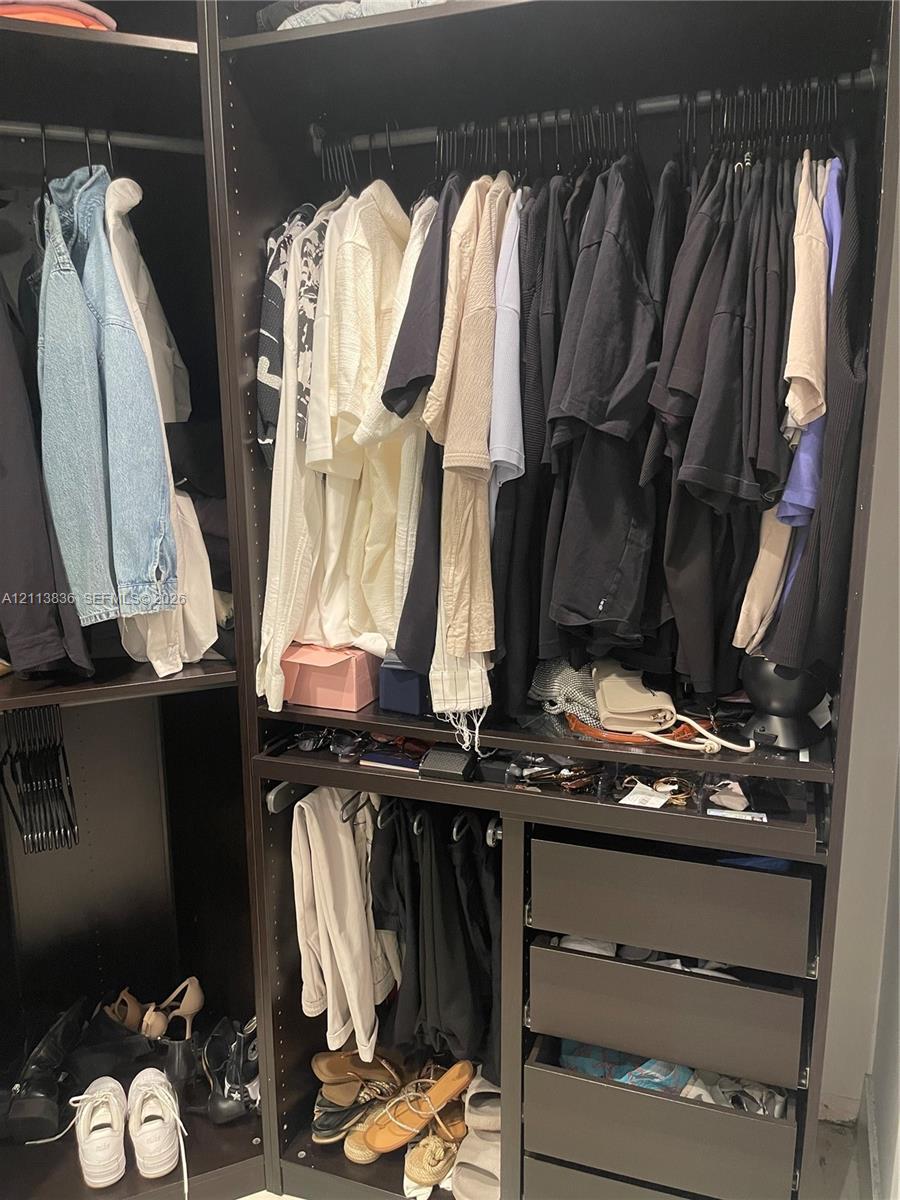 Custom dark-finish cabinetry featuring multiple hanging rods, open shelving, and integrated stacked storage drawers