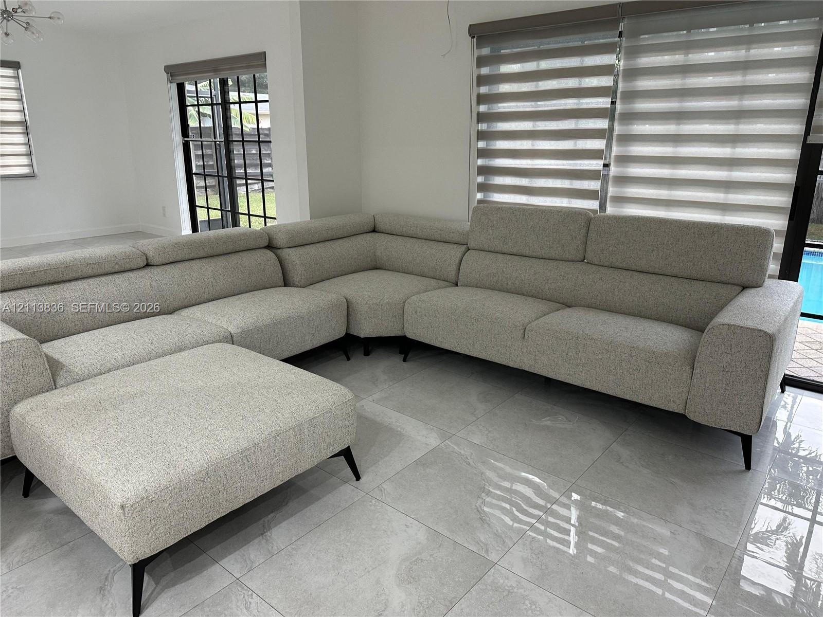 Large-format tile flooring, oversized black-framed sliding glass doors, and dual-layered window treatments