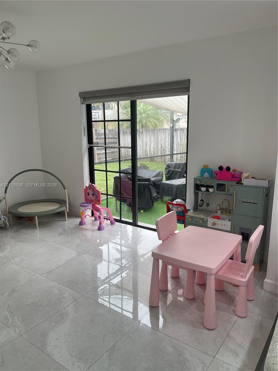 Large-format polished tile flooring, sliding glass door with black grid frames, and modern multi-arm chandelier