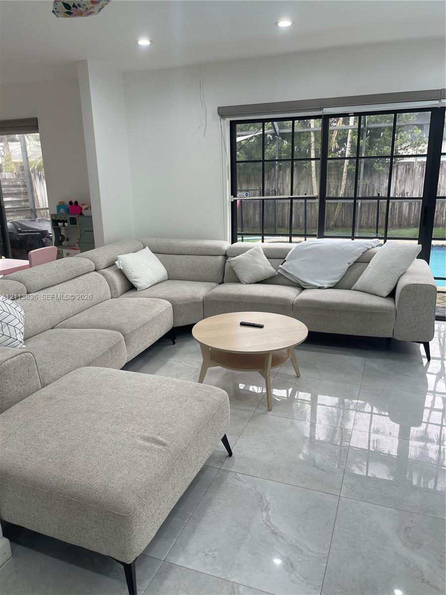 Large-format polished tile flooring, black-framed multi-pane sliding glass door, and recessed ceiling lighting Large-format polished tile flooring, black-framed multi-pane sliding glass door, and recessed ceiling lighting