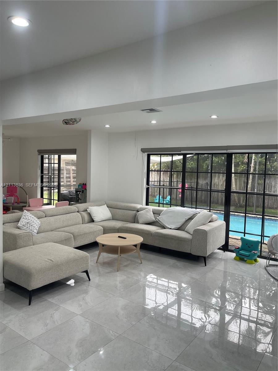 Polished stone-finish flooring, recessed lighting, and black-framed glass sliding doors opening to an exterior swimming pool Polished stone-finish flooring, recessed lighting, and black-framed glass sliding doors opening to an exterior swimming pool