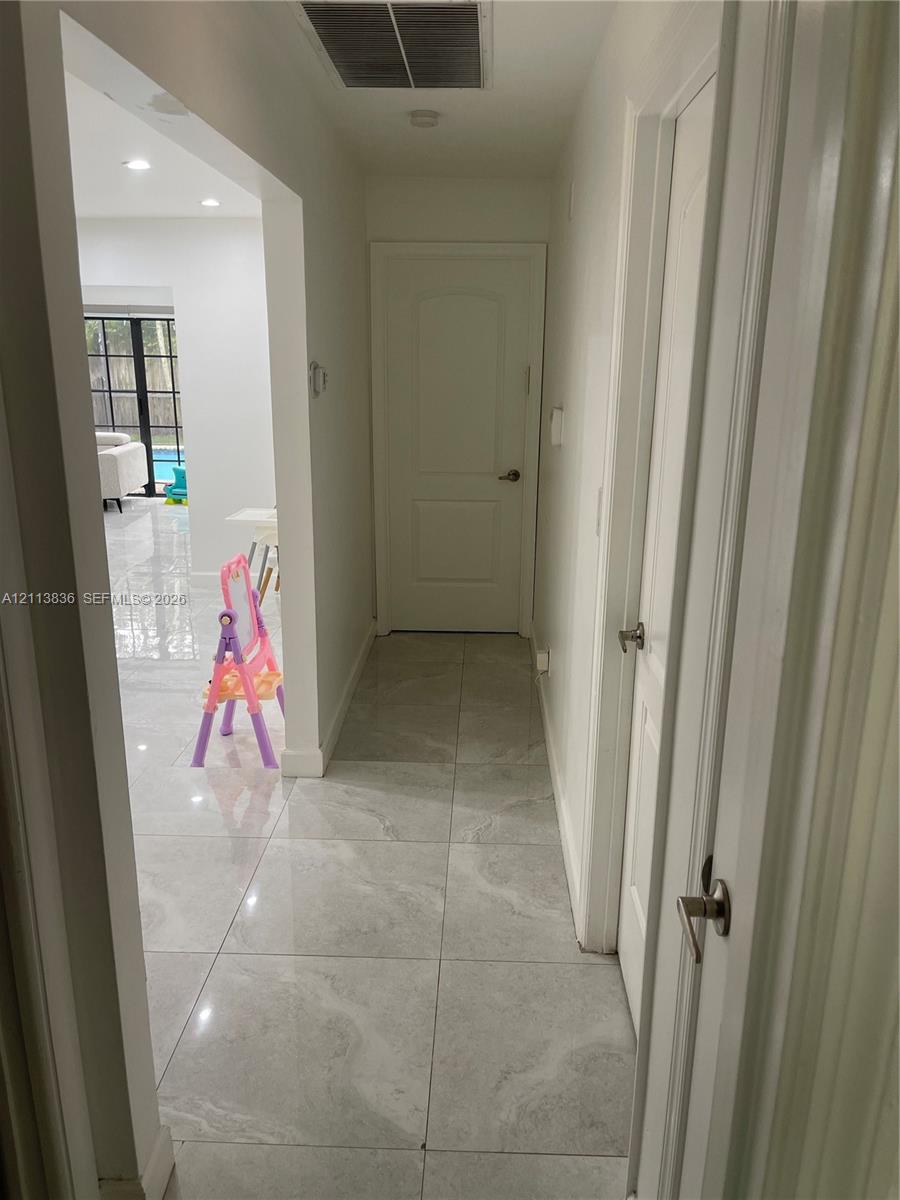 Neutral-toned large-format tile flooring, crisp white walls, and interior doors featuring brushed nickel hardware
