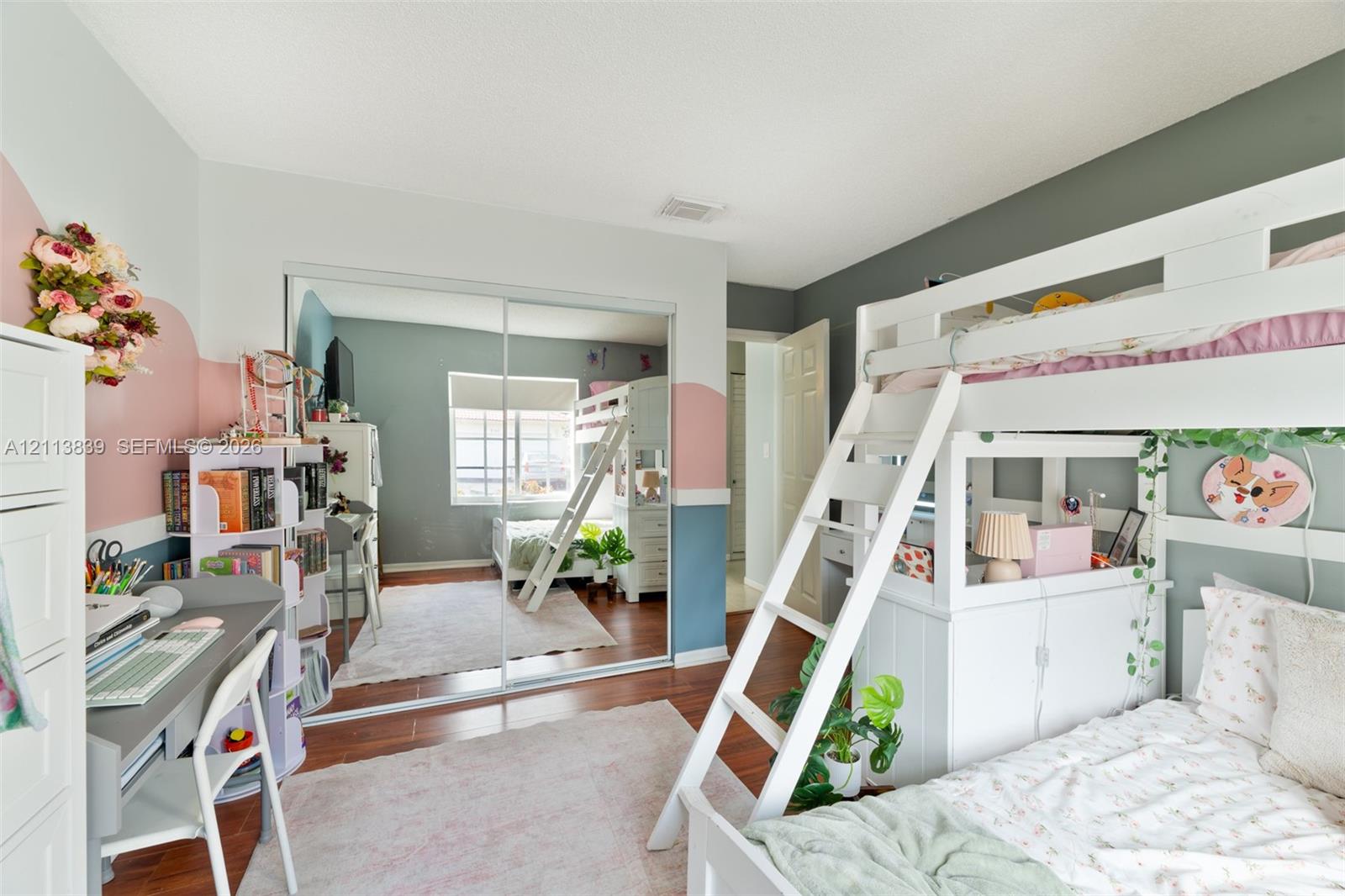Room with wood-finish flooring, sliding mirror-panel closet doors, and neutral wall color palette