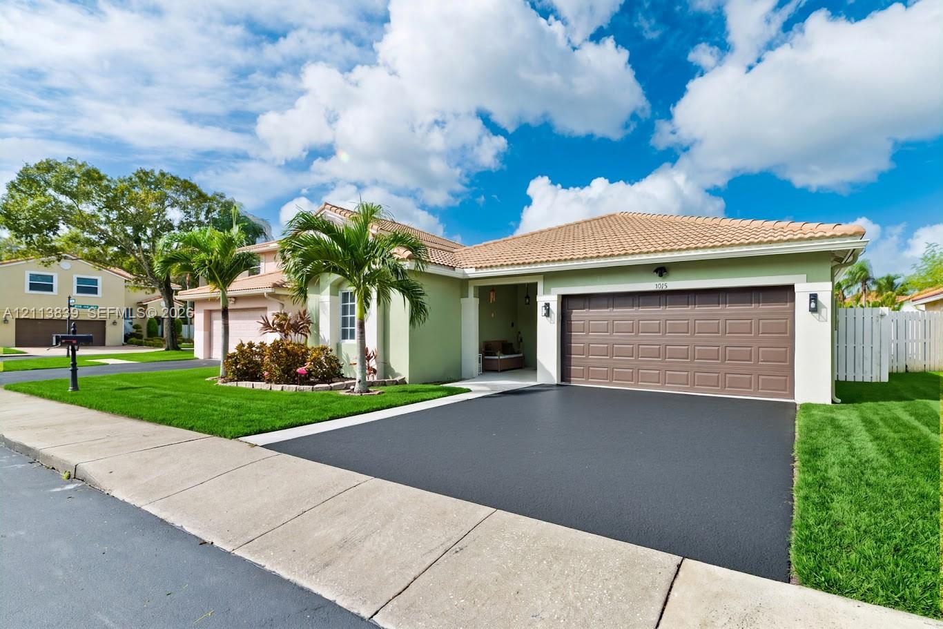 Stucco exterior featuring a tiled roof, multi-panel garage door, asphalt driveway, and manicured lawn