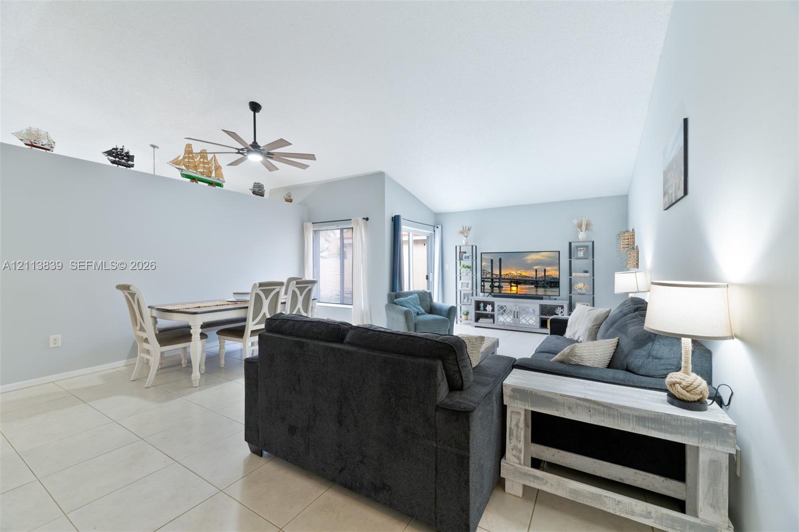 Vaulted ceilings, large-format tile flooring, ceiling fan, and sliding glass door