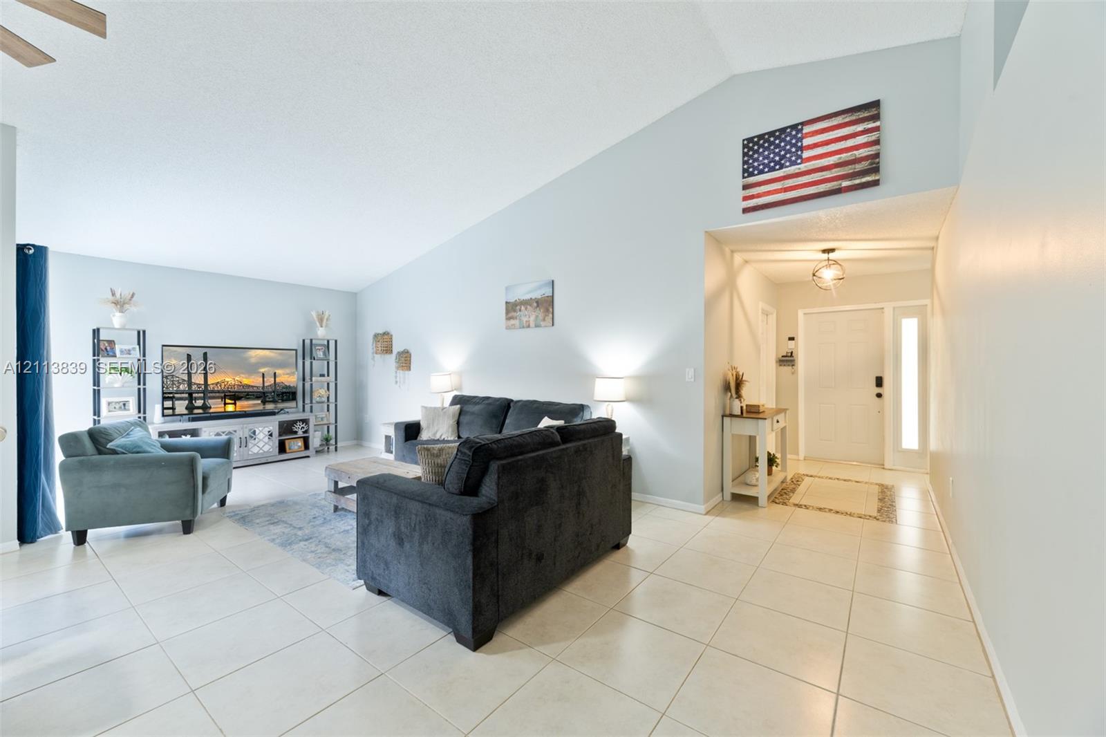 Vaulted ceilings, neutral ceramic tile flooring, and a glass-paneled entry door